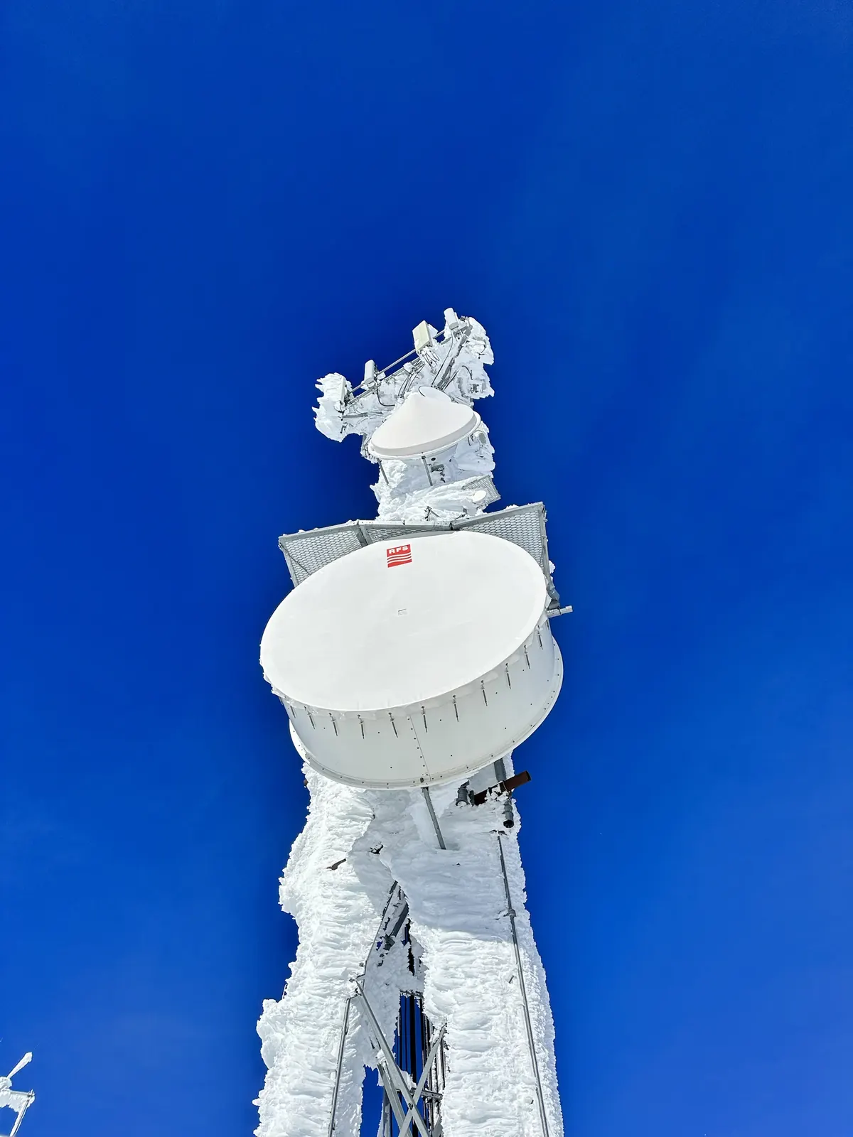 Ice-covered microwave dish on a mountaintop tower